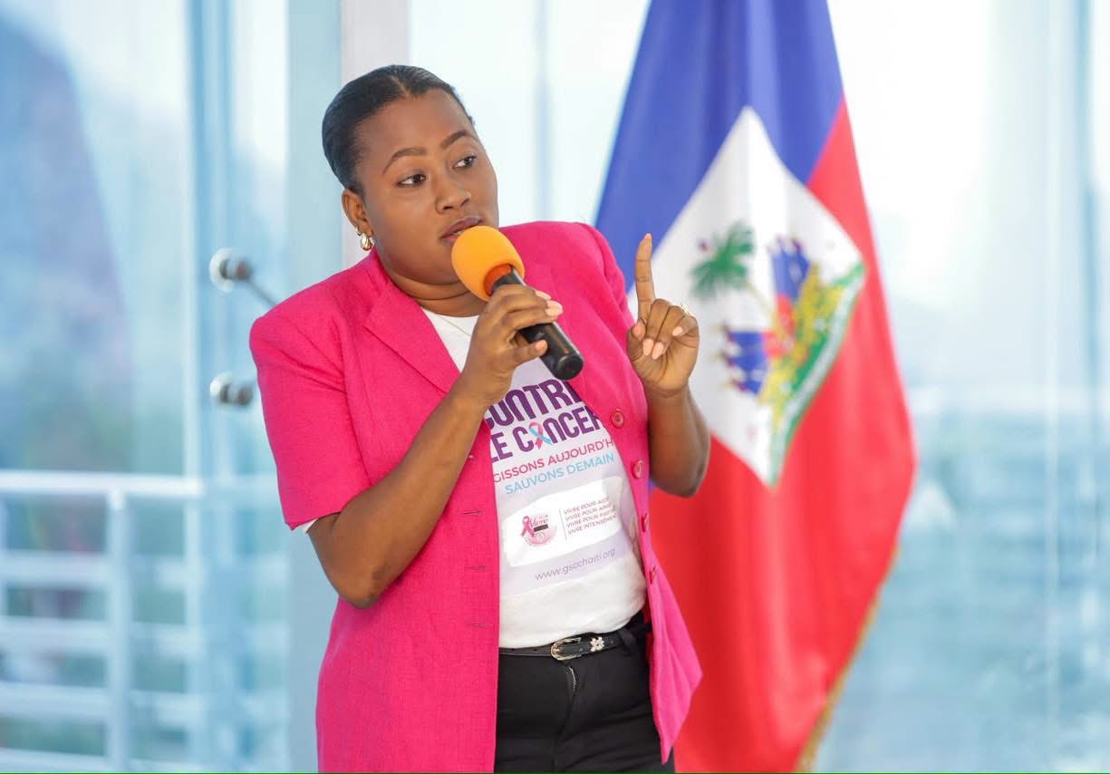 Intervenante en veste rose sensibilisant les participants à la lutte contre le cancer du sein en Haïti
